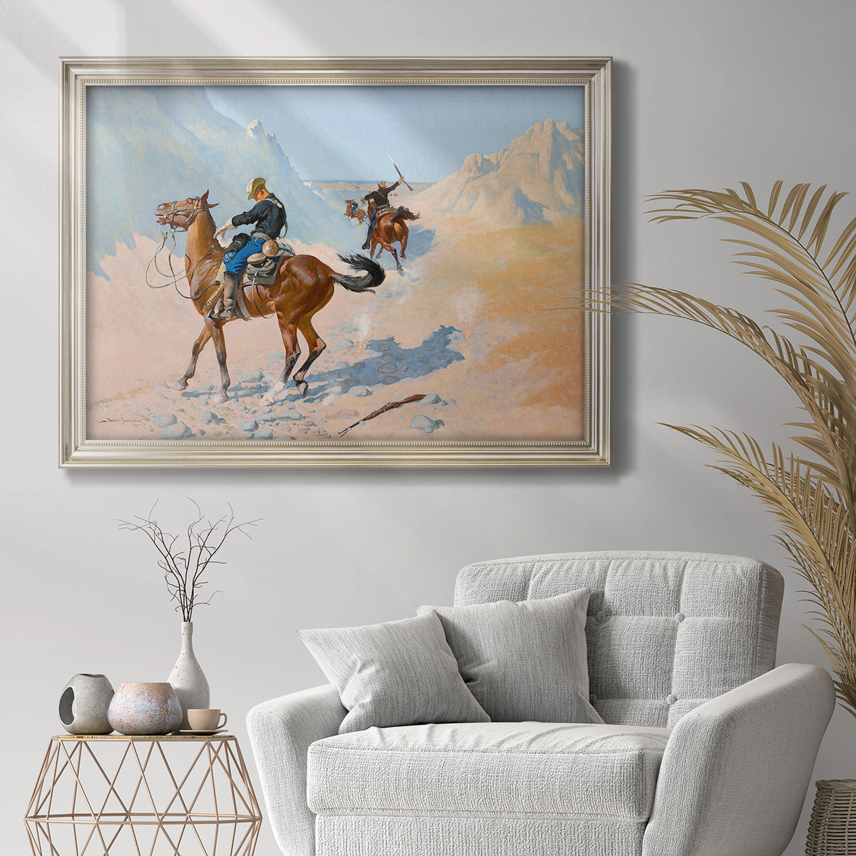 Impressionist western frontier scene by Frederic Remington in an ornate champagne frame displayed in a bright interior setting.