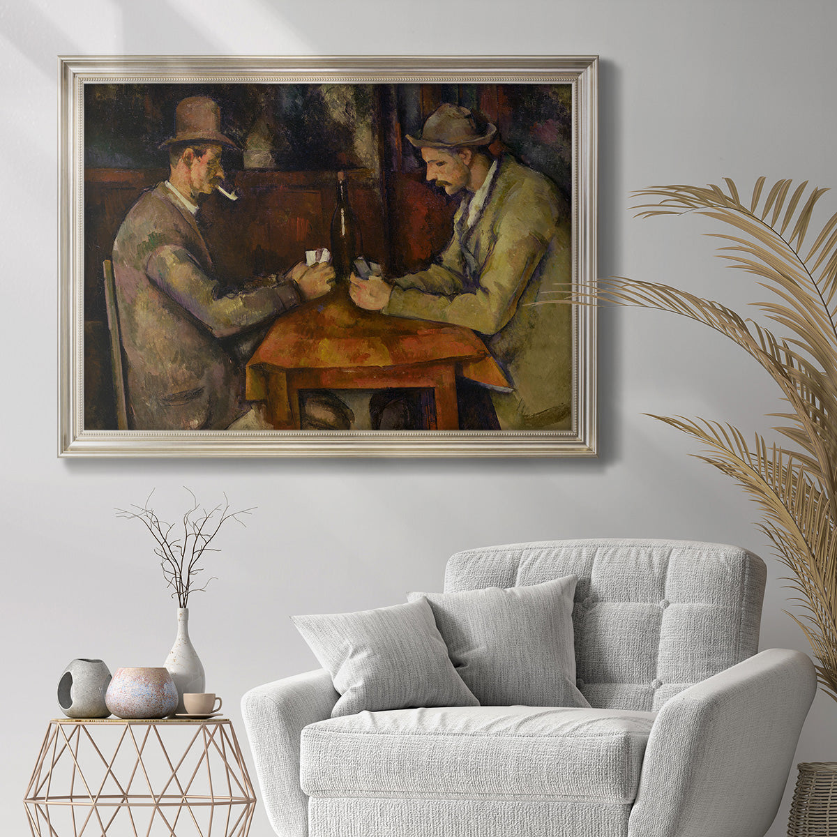 Post-impressionist genre scene of card players by Paul Cézanne in an ornate champagne frame displayed in a bright interior setting.