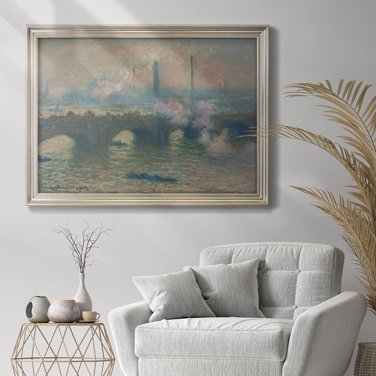 Impressionist overcast city bridge scene by Claude Monet in an ornate champagne frame displayed in a bright interior setting.