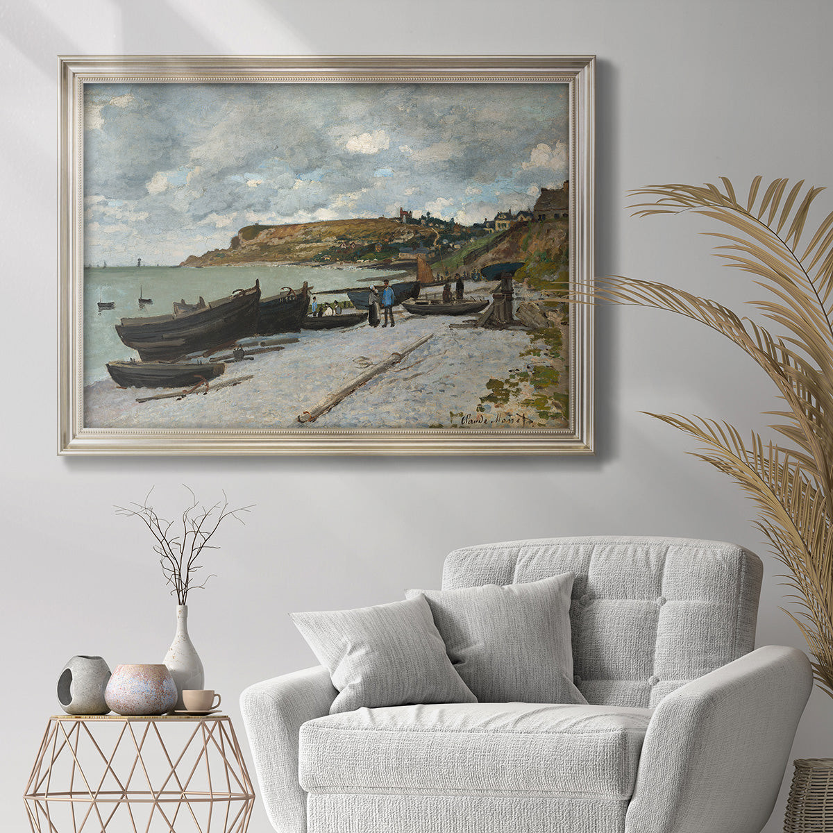 Impressionist coastal seaside scene by Claude Monet in an ornate champagne frame displayed in a bright interior setting.