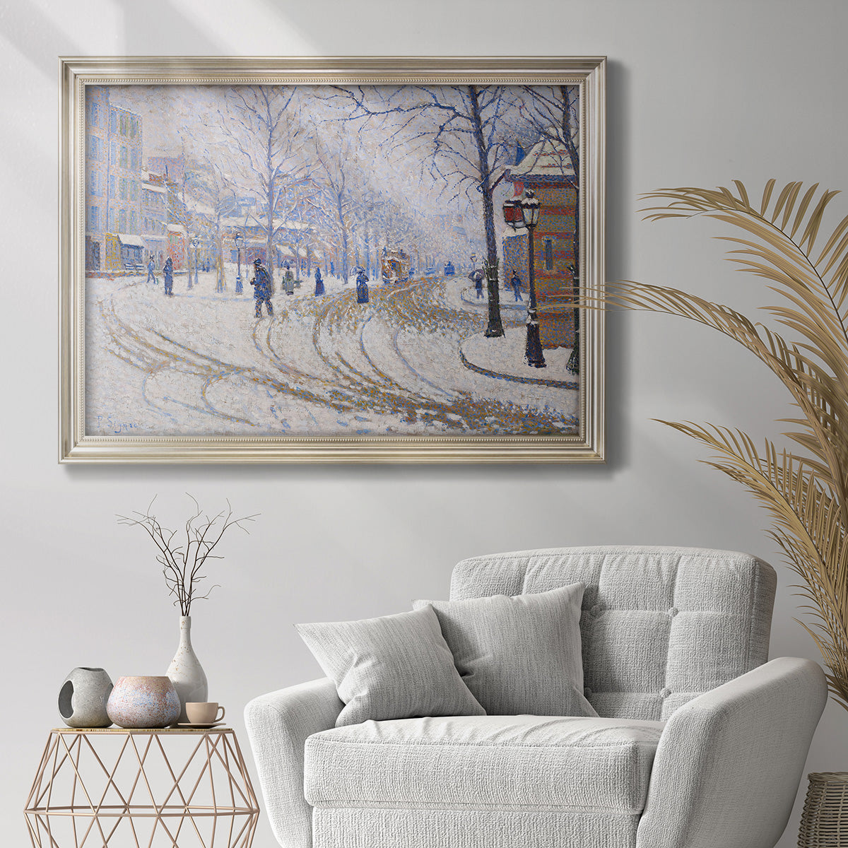 Impressionist winter street scene by Paul Signac in an ornate champagne frame displayed in a bright interior setting.