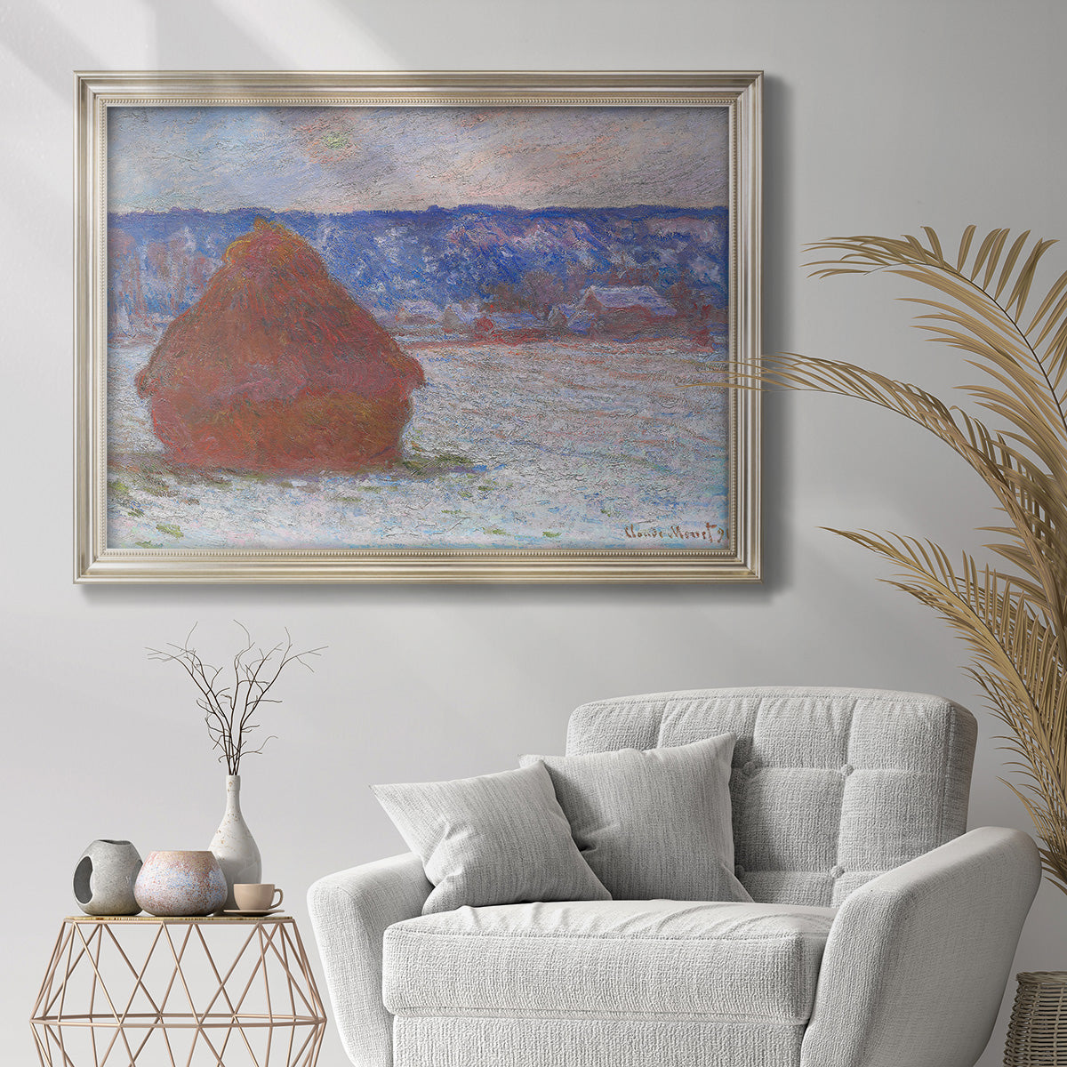 Impressionist winter haystack landscape by Claude Monet in an ornate champagne frame displayed in a bright interior setting.