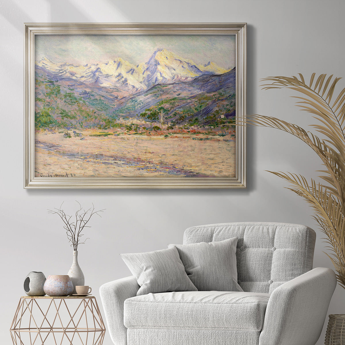 Impressionist valley landscape in southern France by Claude Monet in an ornate champagne frame displayed in a bright interior setting.