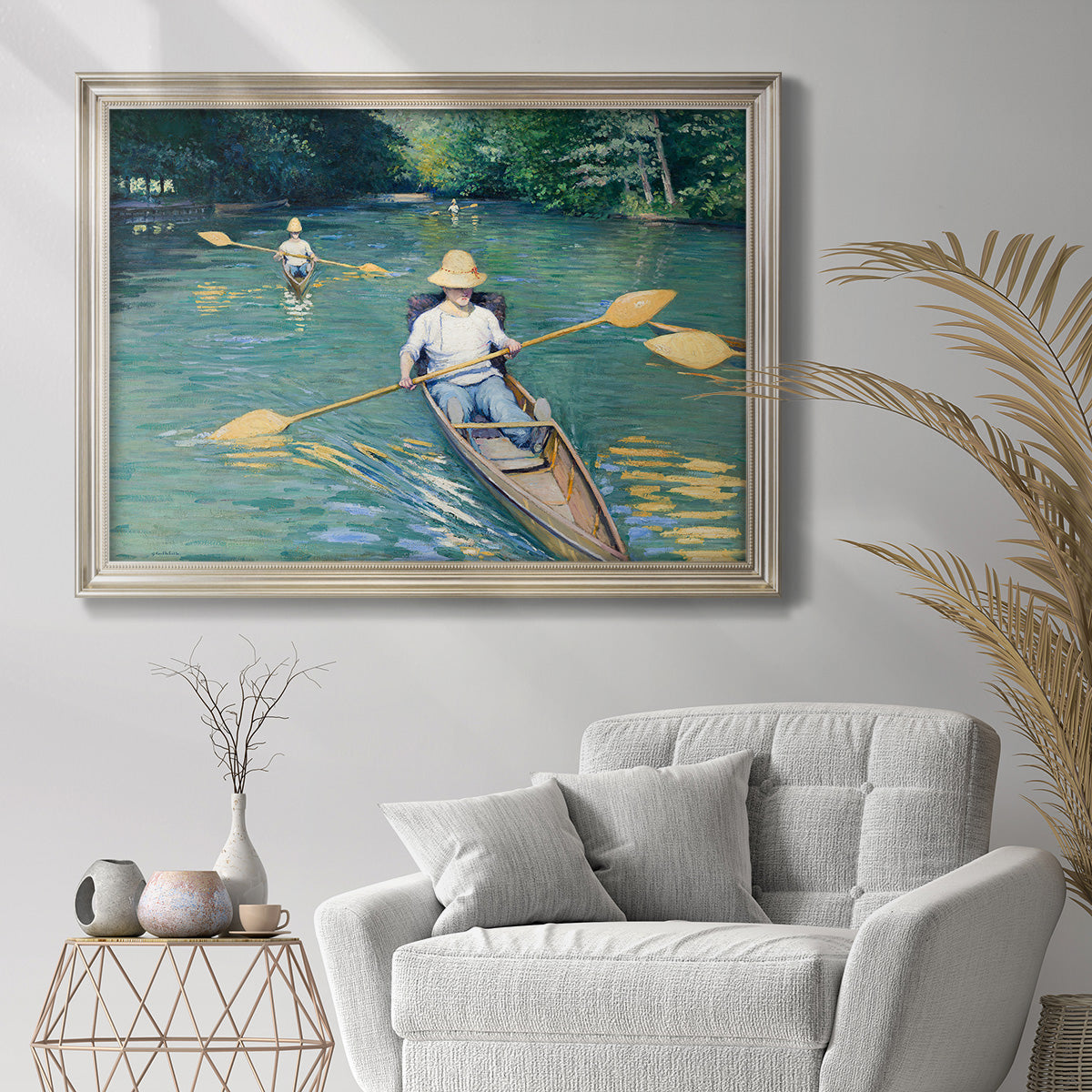 Impressionist river scene with skiffs by Gustave Caillebotte in an ornate champagne frame displayed in a bright interior setting.