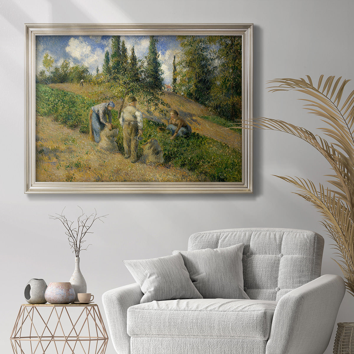 Impressionist countryside harvest scene by Camille Pissarro in an ornate champagne frame displayed in a bright interior setting.
