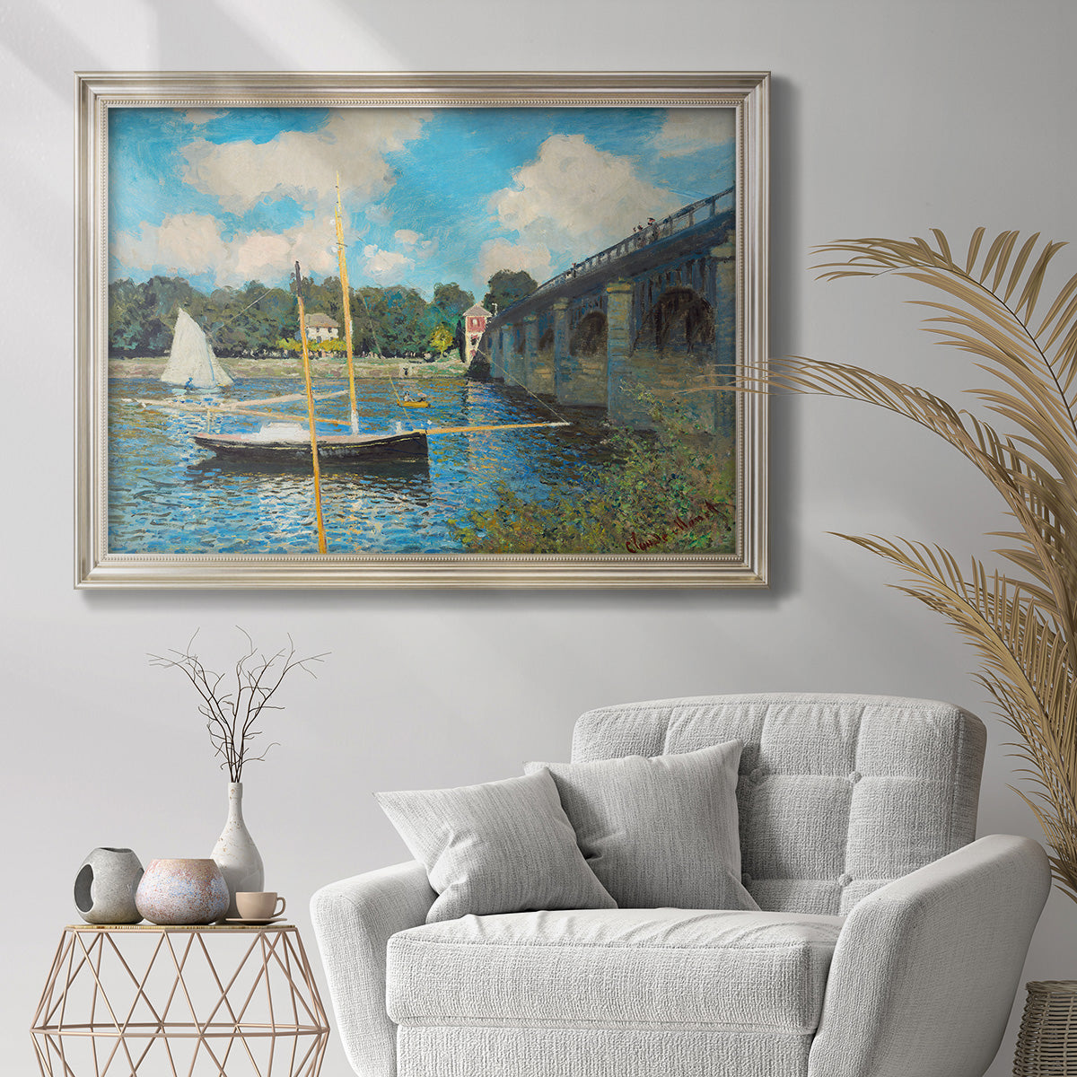 Impressionist river bridge scene at Argenteuil by Claude Monet in an ornate champagne frame displayed in a bright interior setting.