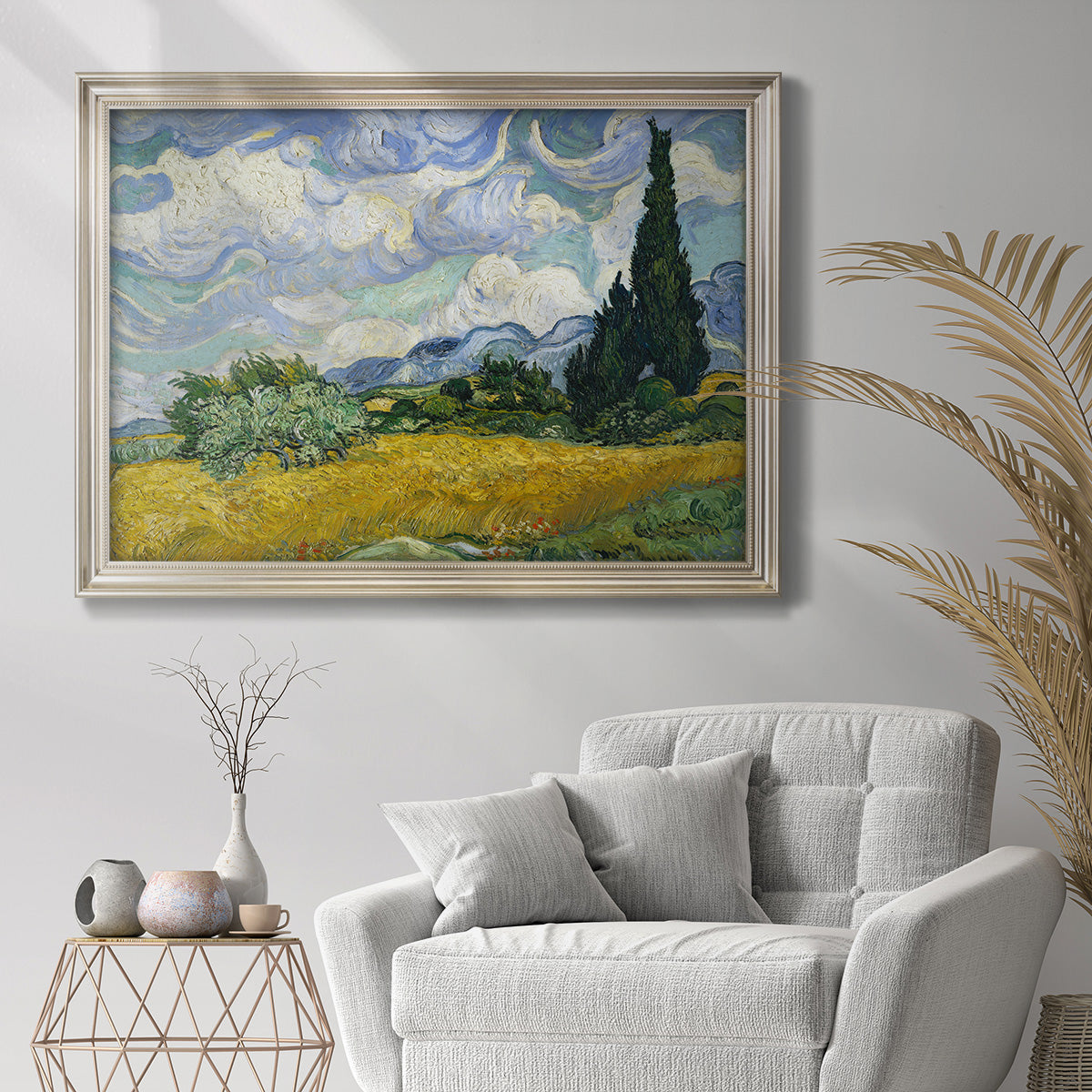Impressionist wheat field with cypress trees by Vincent van Gogh in an ornate champagne frame displayed in a bright interior setting.