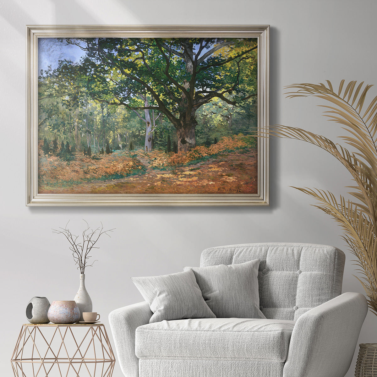 Impressionist forest landscape at Fontainebleau by Claude Monet in an ornate champagne frame displayed in a bright interior setting.