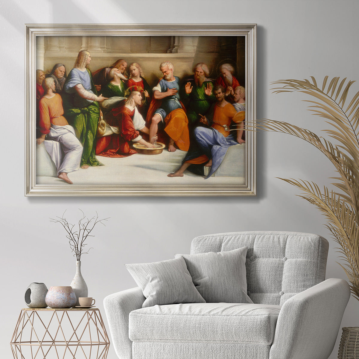 Classical religious painting depicting Christ washing feet by Benvenuto Tisi in an ornate champagne frame displayed in a bright interior setting.