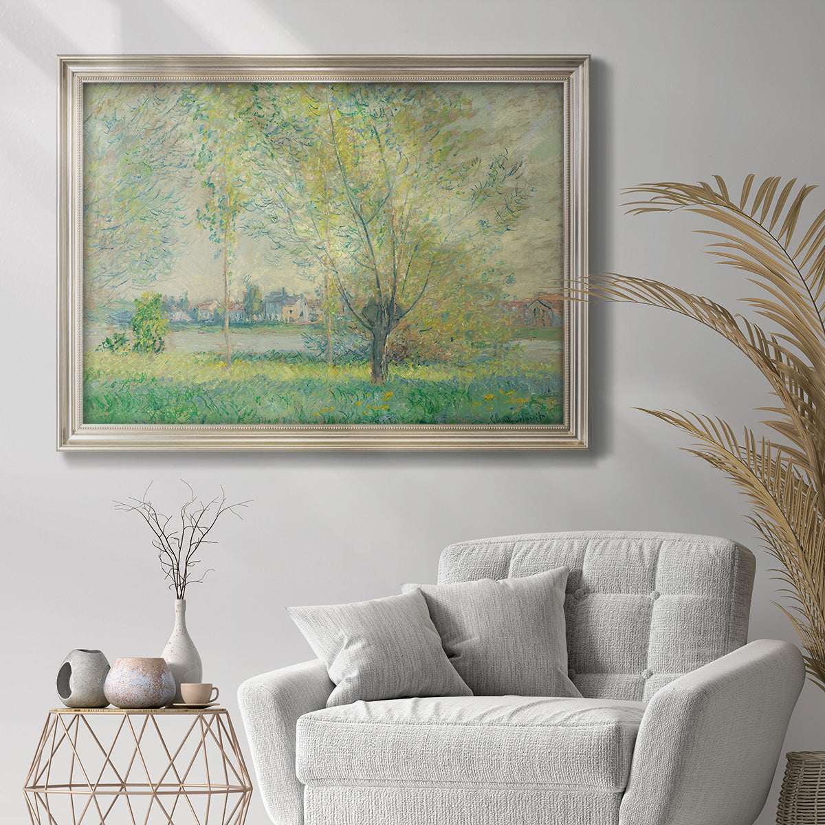 Impressionist willow tree riverbank landscape by Claude Monet in an ornate champagne frame displayed in a bright interior setting.