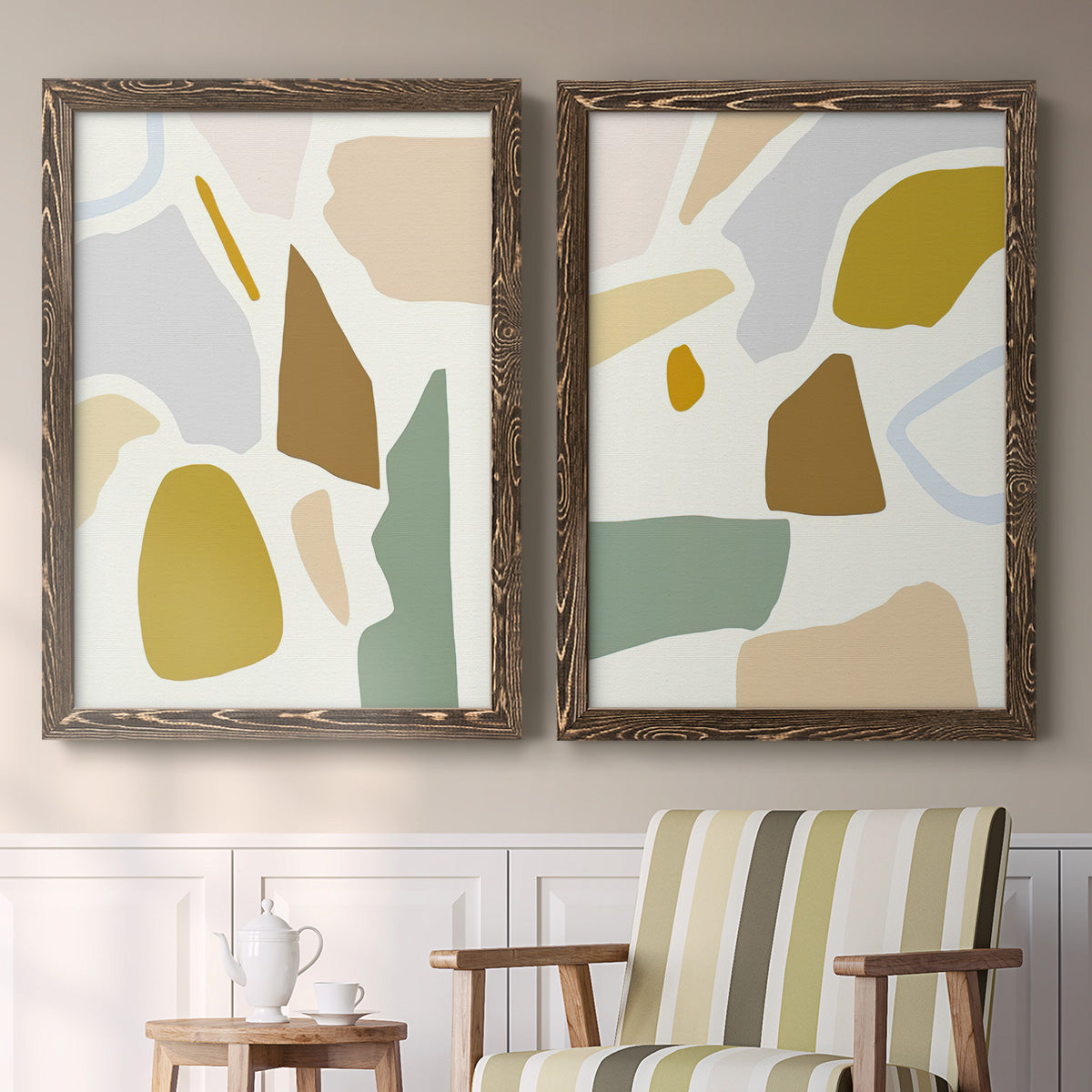 Set of two walnut barnwood framed canvas prints depicting two pastel geometric abstracts featuring soft mustard sage gray and white irregular shapes above a sideboard in a cozy sitting room.