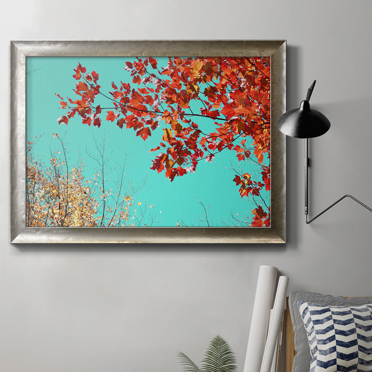 Red autumn leaves against a blue sky in an ornate mottled silver frame displayed in a neutral interior setting.