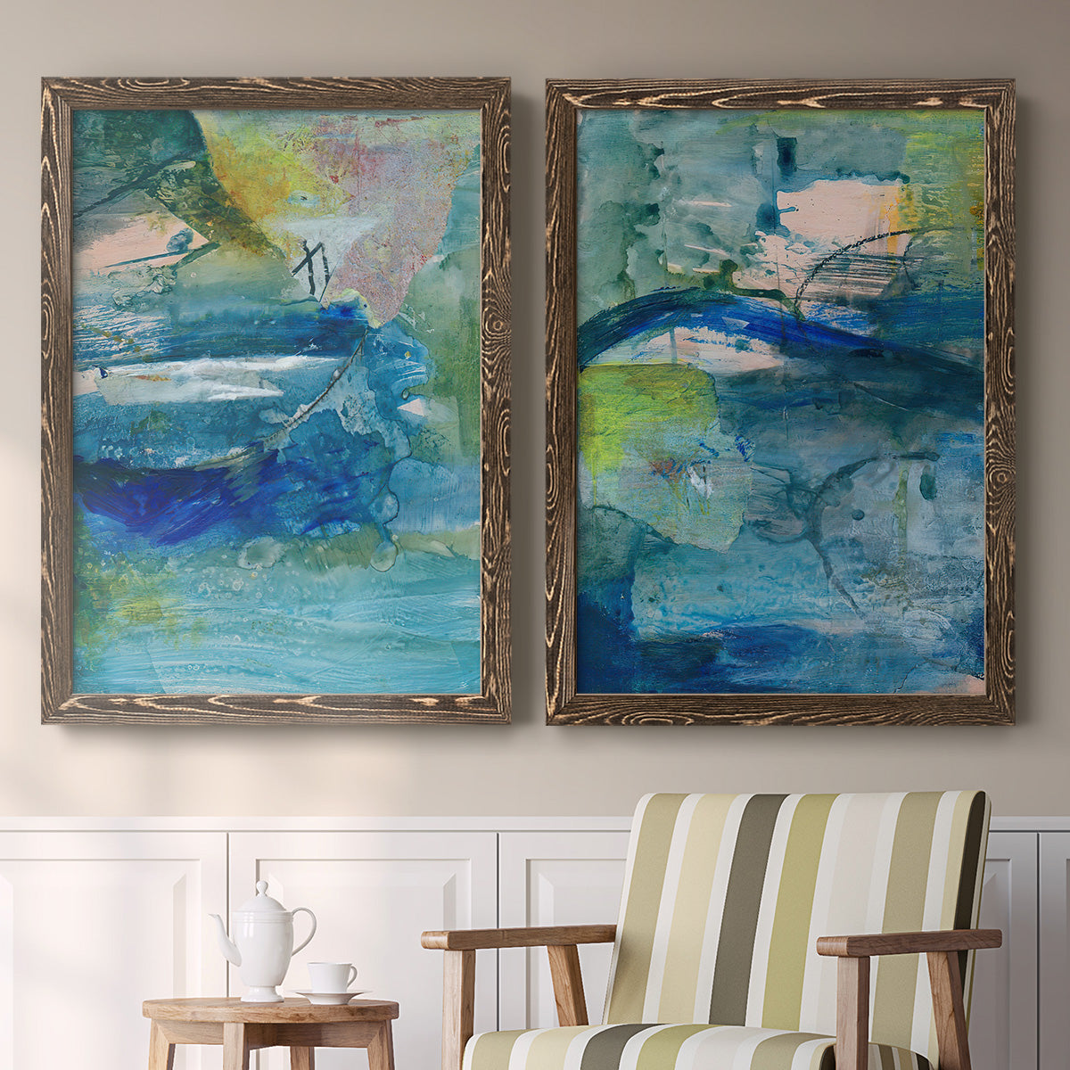 Set of two walnut barnwood framed canvas prints depicting two energetic mixed-media abstracts featuring layered blue teal green and yellow painterly fields above a sideboard in a cozy sitting room.