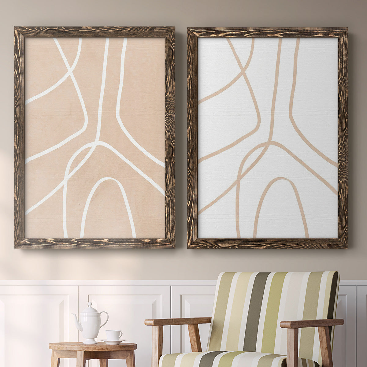 Set of two walnut barnwood framed canvas prints depicting two minimalist line abstracts featuring single continuous tan lines forming oversized organic curves above a sideboard in a cozy sitting room.
