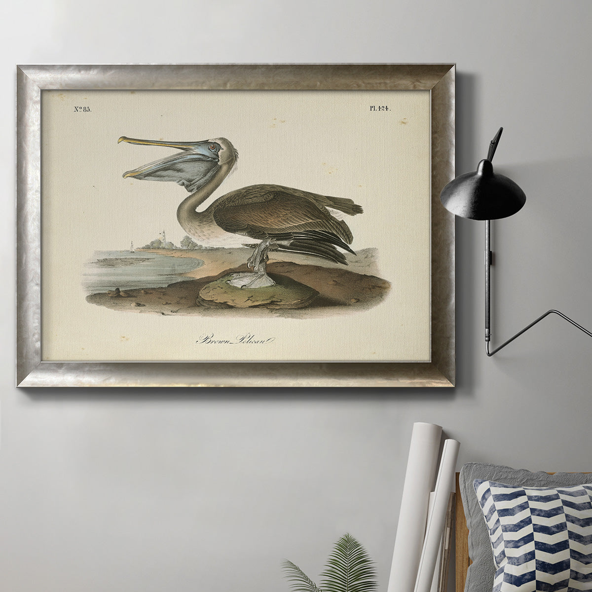 Antique brown pelican bird illustration by John James Audubon in an ornate mottled silver frame displayed in a neutral interior setting.