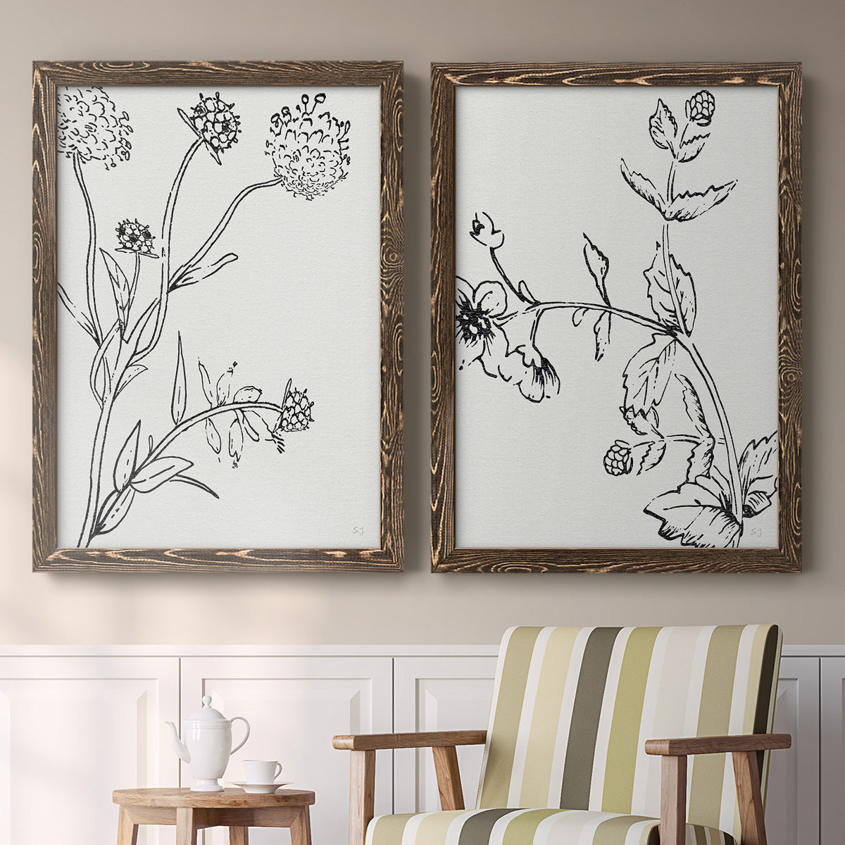 Set of two walnut barnwood framed canvas prints depicting two minimalist botanical sketches featuring black line drawings of wildflowers and leaves above a sideboard in a cozy sitting room.