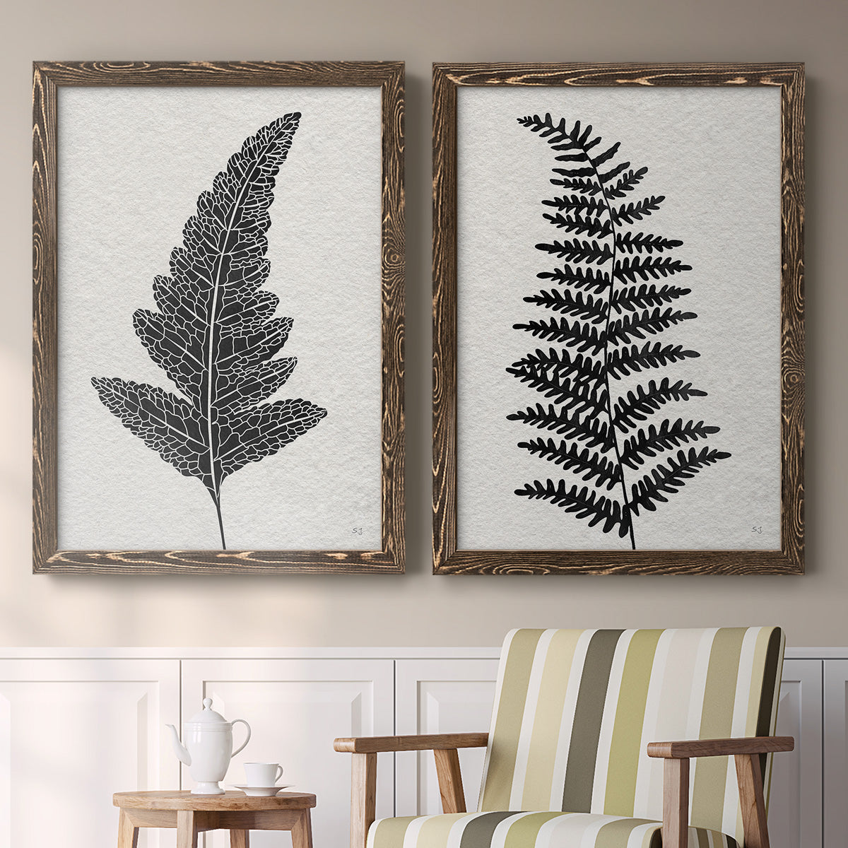 Set of two walnut barnwood framed canvas prints depicting two minimalist botanical prints featuring black fern leaf silhouettes above a sideboard in a cozy sitting room.