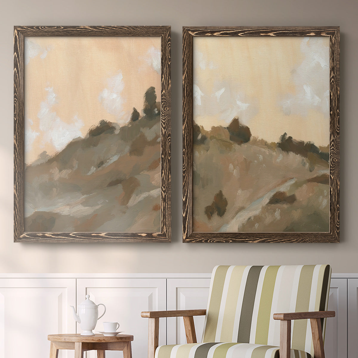 Set of two walnut barnwood framed canvas prints depicting two minimalist watercolor landscapes featuring misty brown hills and winding mountain paths above a sideboard in a cozy sitting room.