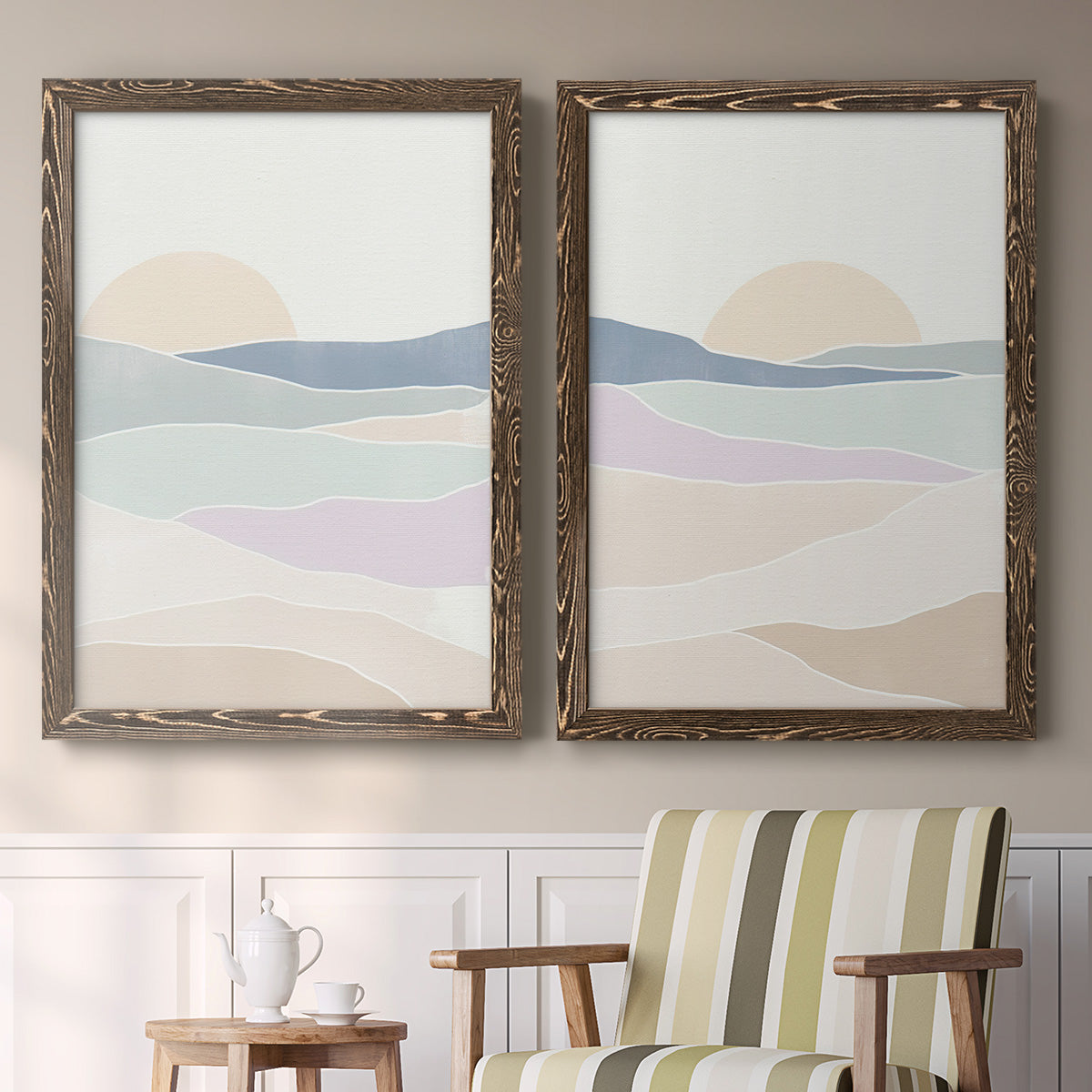 Set of two walnut barnwood framed canvas prints depicting two minimalist abstract landscapes featuring layered pastel waves beneath a pale setting sun above a sideboard in a cozy sitting room.