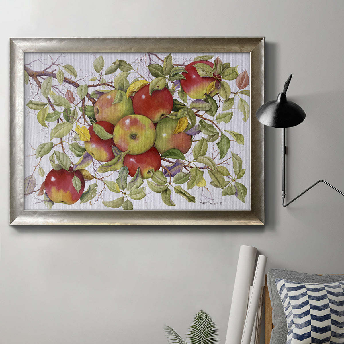Classic still life painting of apples in an ornate mottled silver frame displayed in a neutral interior setting.