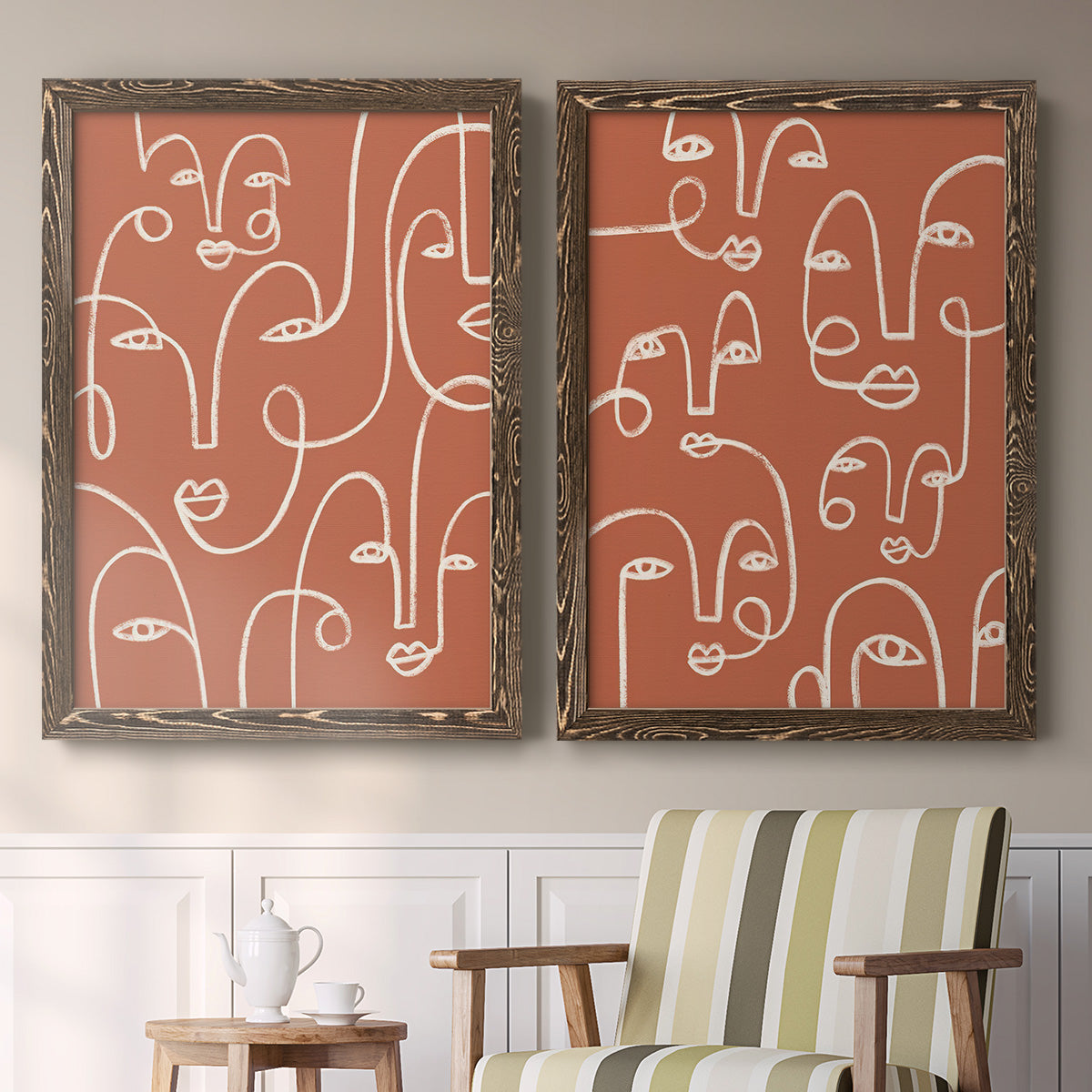 Set of two walnut barnwood framed canvas prints depicting two graphic portrait patterns featuring many continuous-line faces across terracotta grounds above a sideboard in a cozy sitting room.