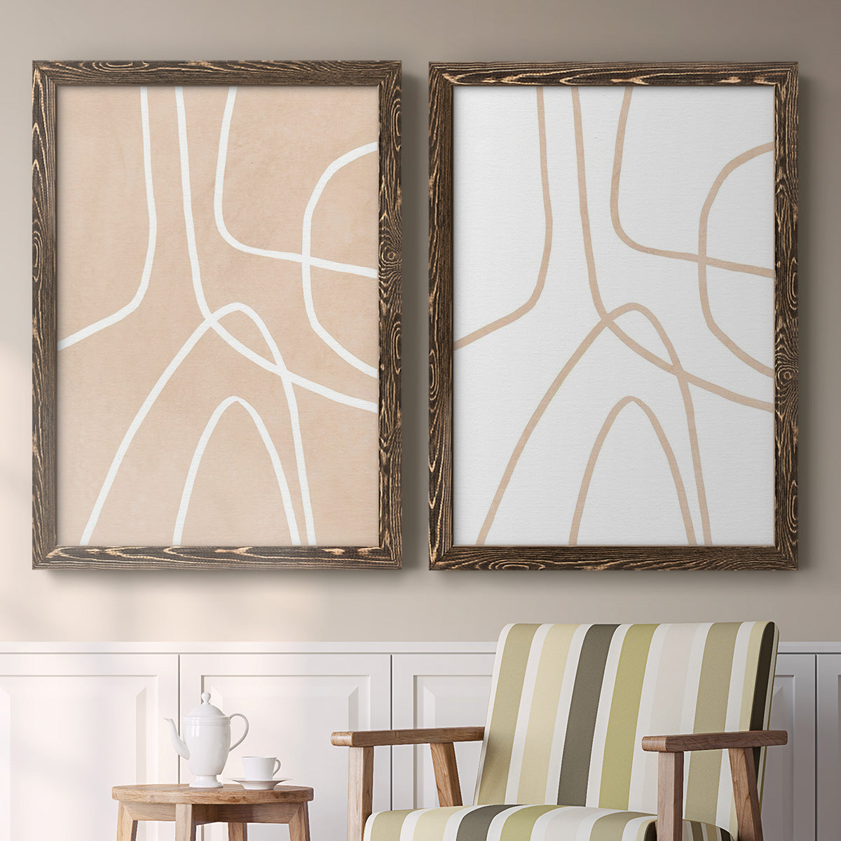 Set of two walnut barnwood framed canvas prints depicting two minimalist line abstracts featuring single continuous tan lines forming oversized organic curves above a sideboard in a cozy sitting room.