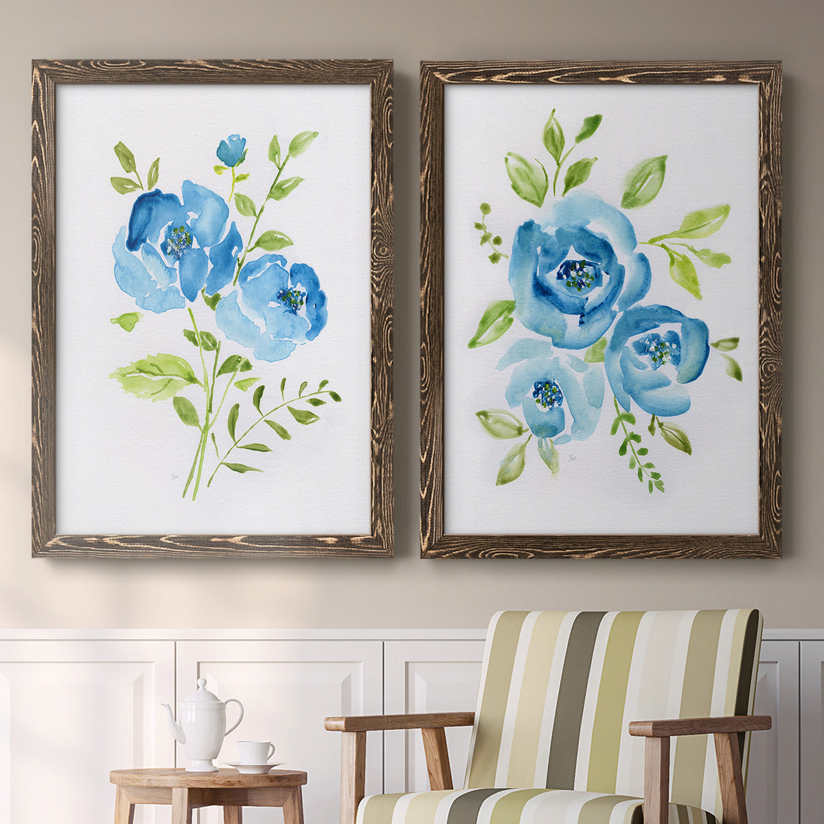 Set of two walnut barnwood framed canvas prints depicting two contemporary botanical paintings featuring blue watercolor flowers with fresh green leaves above a sideboard in a cozy sitting room.