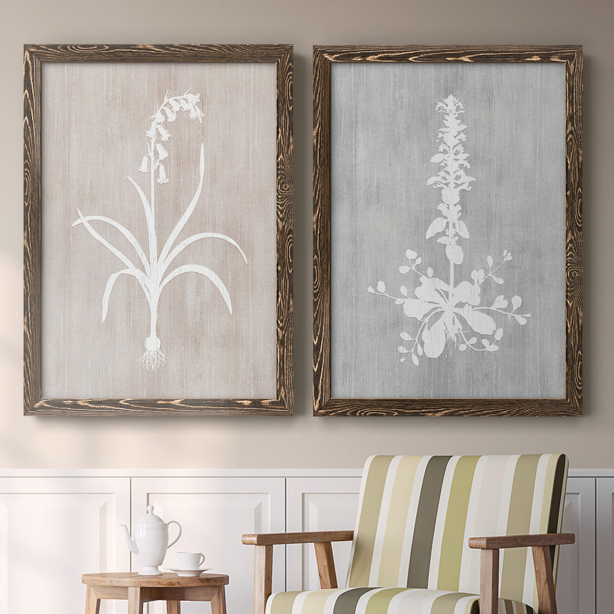 Set of two walnut barnwood framed canvas prints depicting two rustic minimalist botanical prints featuring white botanical silhouettes on softly weathered neutral backgrounds above a sideboard in a cozy sitting room.