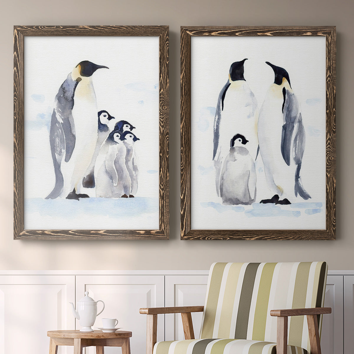 Set of two walnut barnwood framed canvas prints depicting two soft watercolor wildlife illustrations featuring adult emperor penguins with fluffy chicks above a sideboard in a cozy sitting room.