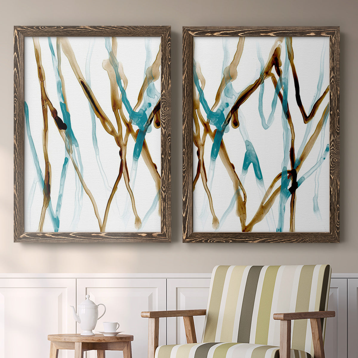 Set of two walnut barnwood framed canvas prints depicting two fluid abstracts with branching turquoise and brown lines drifting across white backgrounds above a sideboard in a cozy sitting room.