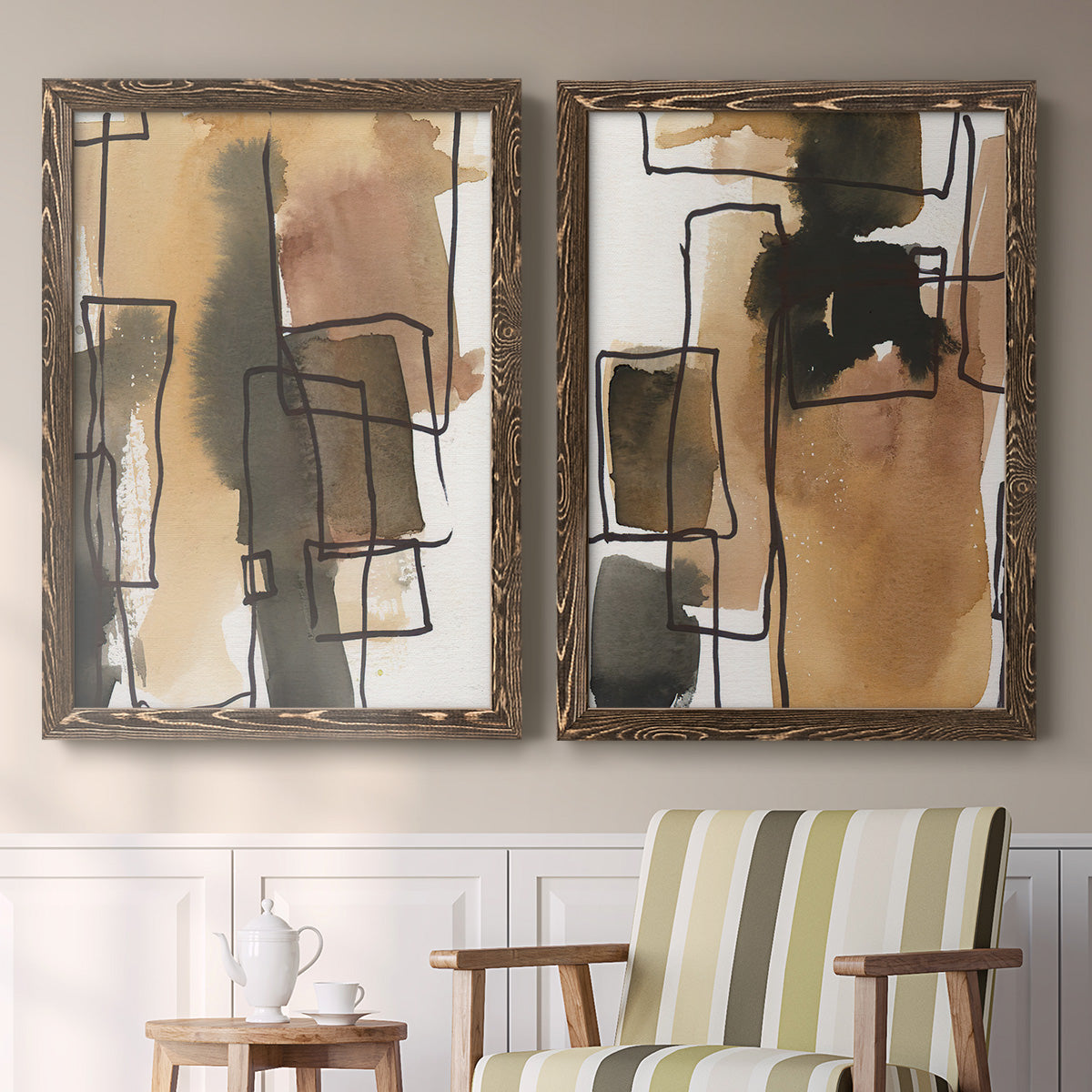 Set of two walnut barnwood framed canvas prints depicting two retro geometric abstracts featuring earthy watercolor blocks crossed by black contour lines above a sideboard in a cozy sitting room.