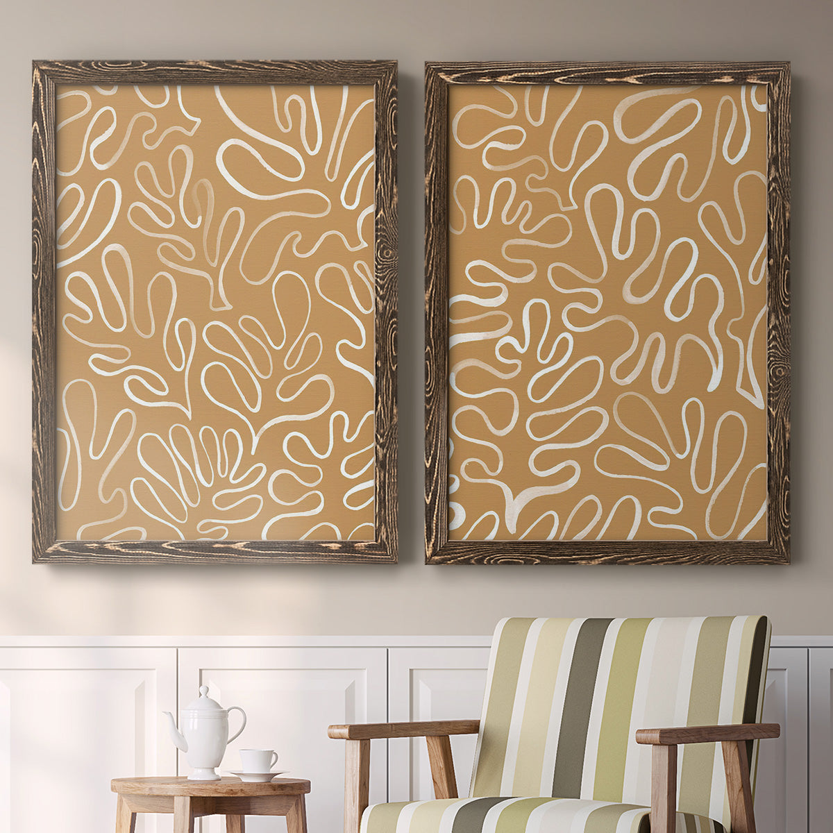Set of two walnut barnwood framed canvas prints depicting two graphic botanical pattern abstracts featuring continuous white organic lines over solid ochre and blush fields above a sideboard in a cozy sitting room.