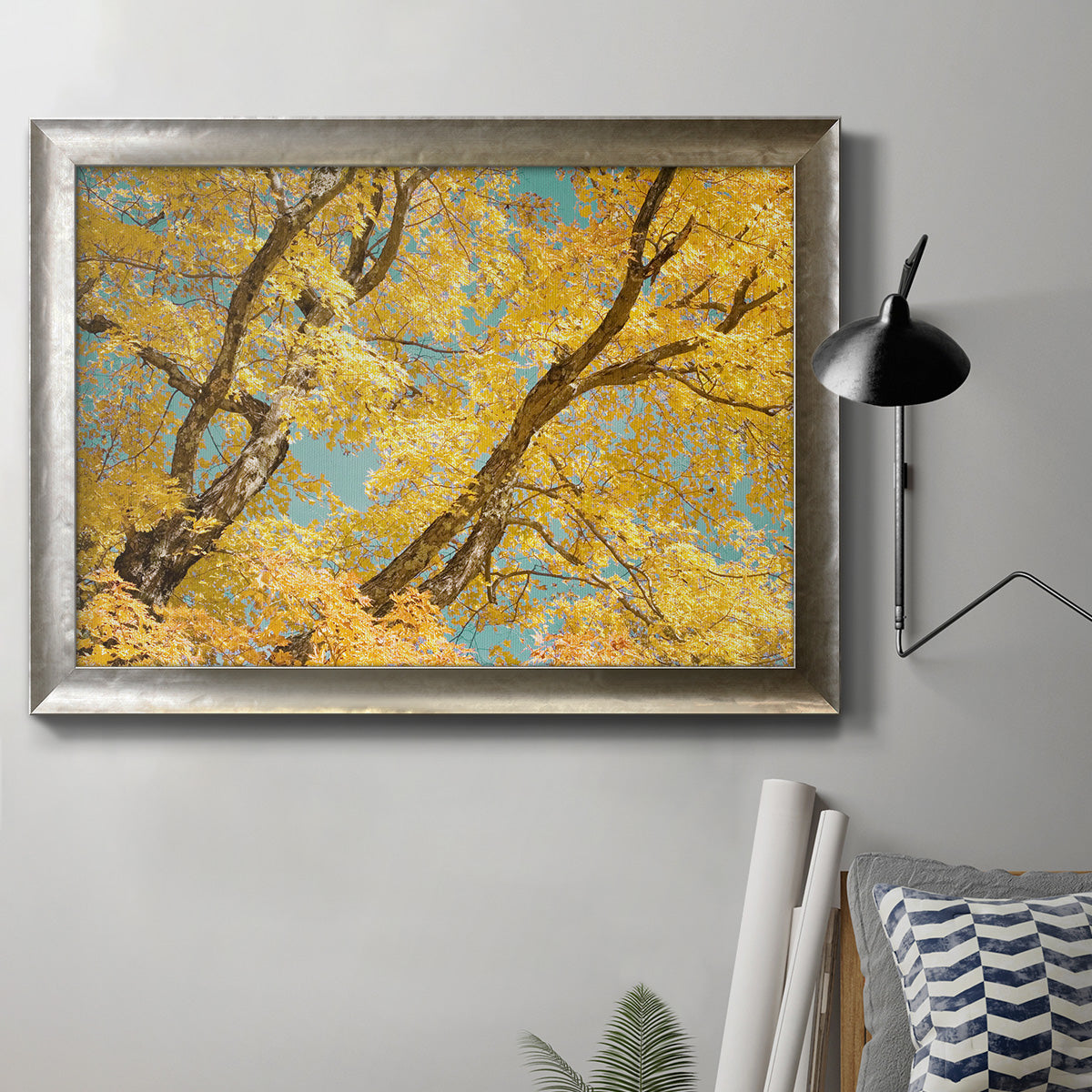 Vibrant yellow autumn leaves on branches in an ornate mottled silver frame displayed in a neutral interior setting.