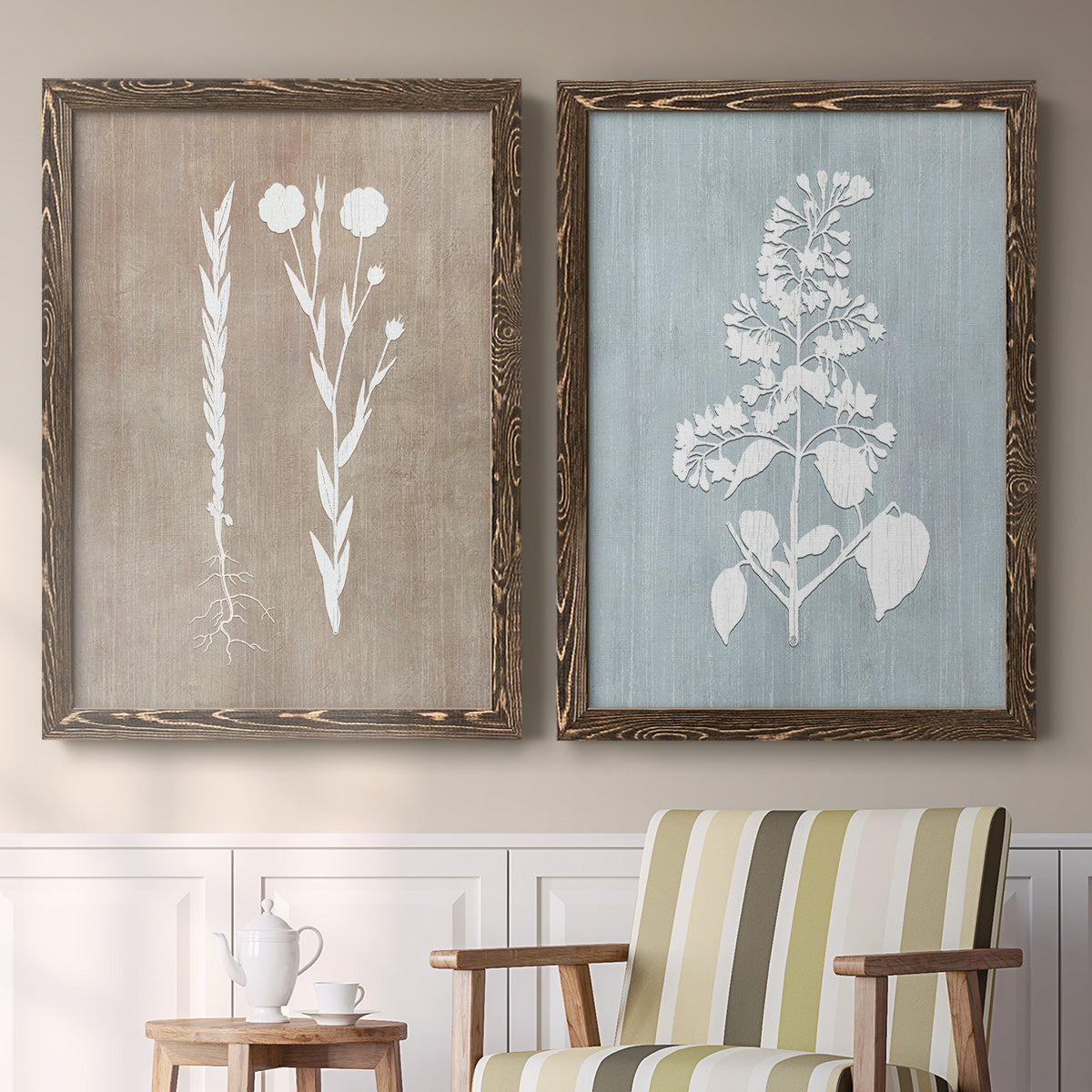 Set of two walnut barnwood framed canvas prints depicting two rustic minimalist botanical prints featuring white botanical silhouettes on softly weathered neutral backgrounds above a sideboard in a cozy sitting room.
