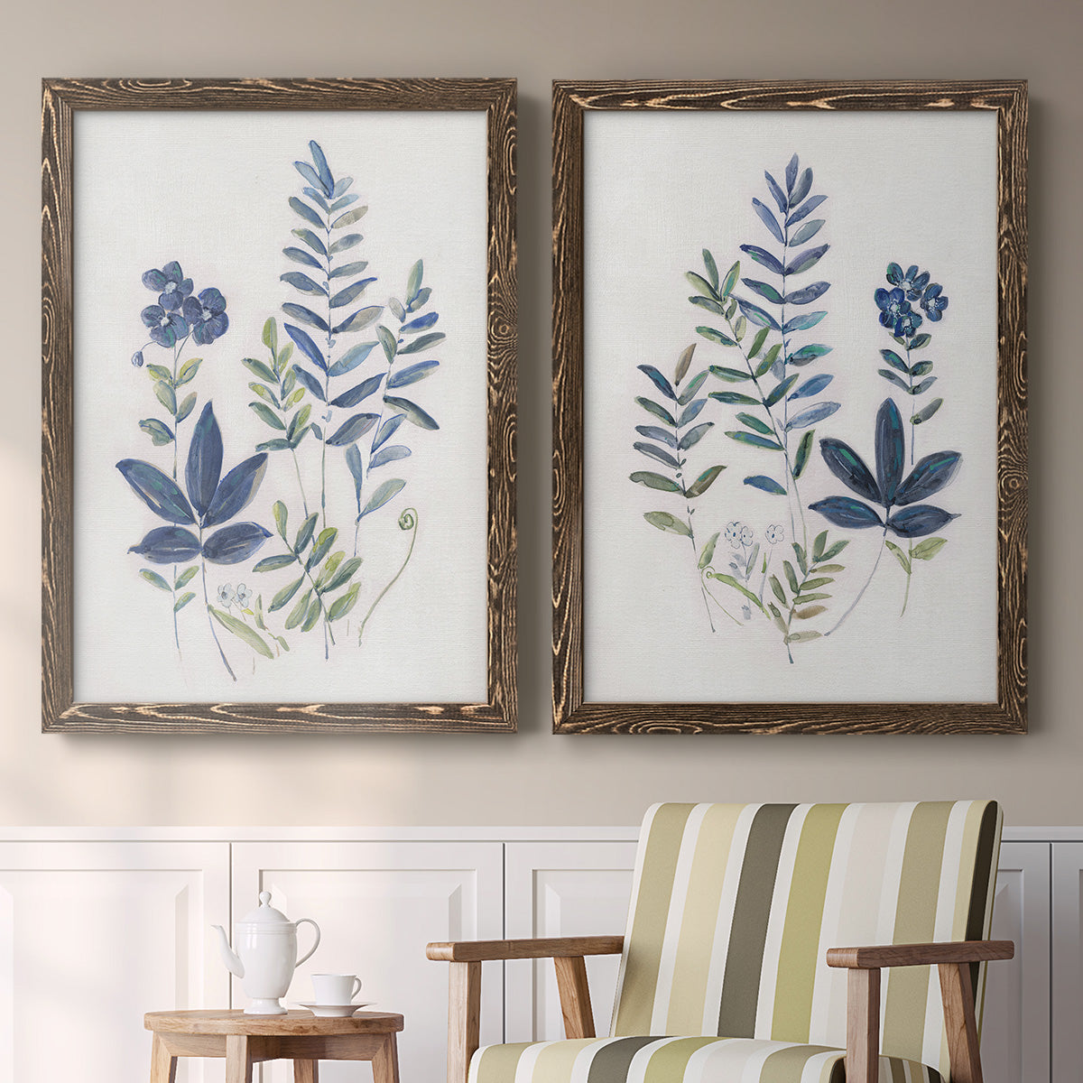 Set of two walnut barnwood framed canvas prints depicting two rustic botanical illustrations featuring blue fern fronds and small woodland flowers above a sideboard in a cozy sitting room.
