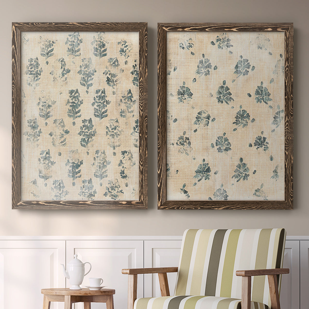 Set of two walnut barnwood framed canvas prints depicting two weathered block-print patterns featuring small repeating blue floral motifs above a sideboard in a cozy sitting room.