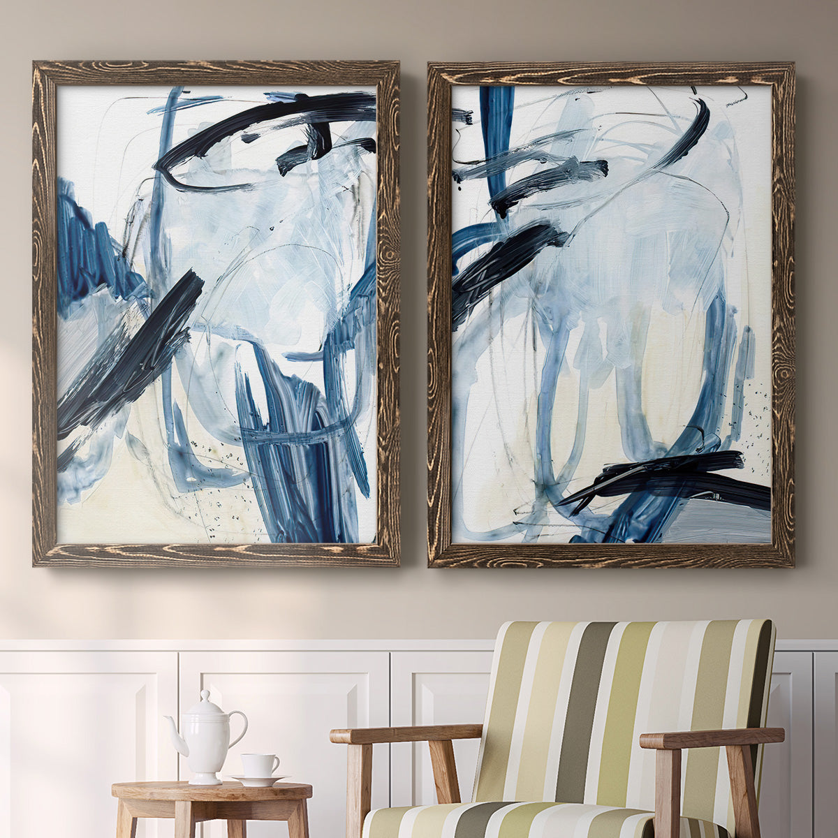Set of two walnut barnwood framed canvas prints depicting two expressive blue abstracts featuring sweeping indigo and black gestural brushwork above a sideboard in a cozy sitting room.