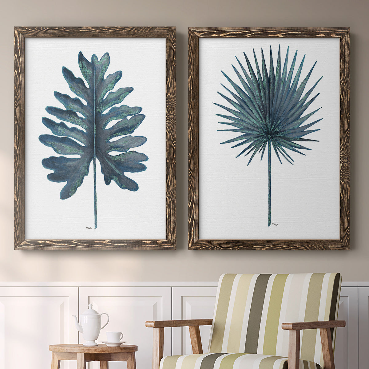 Set of two walnut barnwood framed canvas prints depicting two modern botanical illustrations featuring large blue-green tropical leaves above a sideboard in a cozy sitting room.