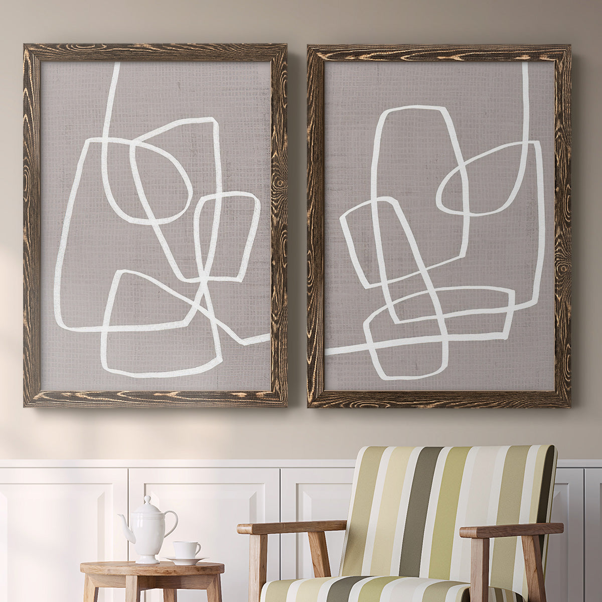 Set of two walnut barnwood framed canvas prints depicting two minimalist geometric line art featuring overlapping white continuous-line loops on taupe above a sideboard in a cozy sitting room.