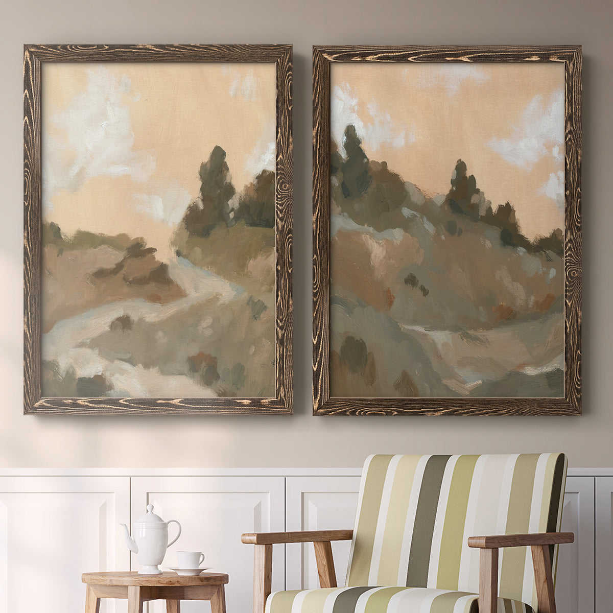 Set of two walnut barnwood framed canvas prints depicting two minimalist watercolor landscapes featuring misty brown hills and winding mountain paths above a sideboard in a cozy sitting room.