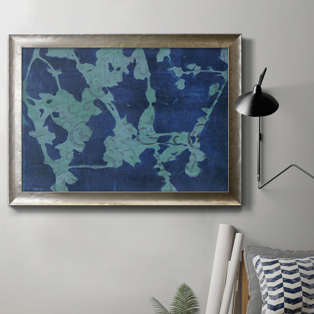 Blue abstract botanical in an ornate mottled silver frame displayed in a neutral interior setting.