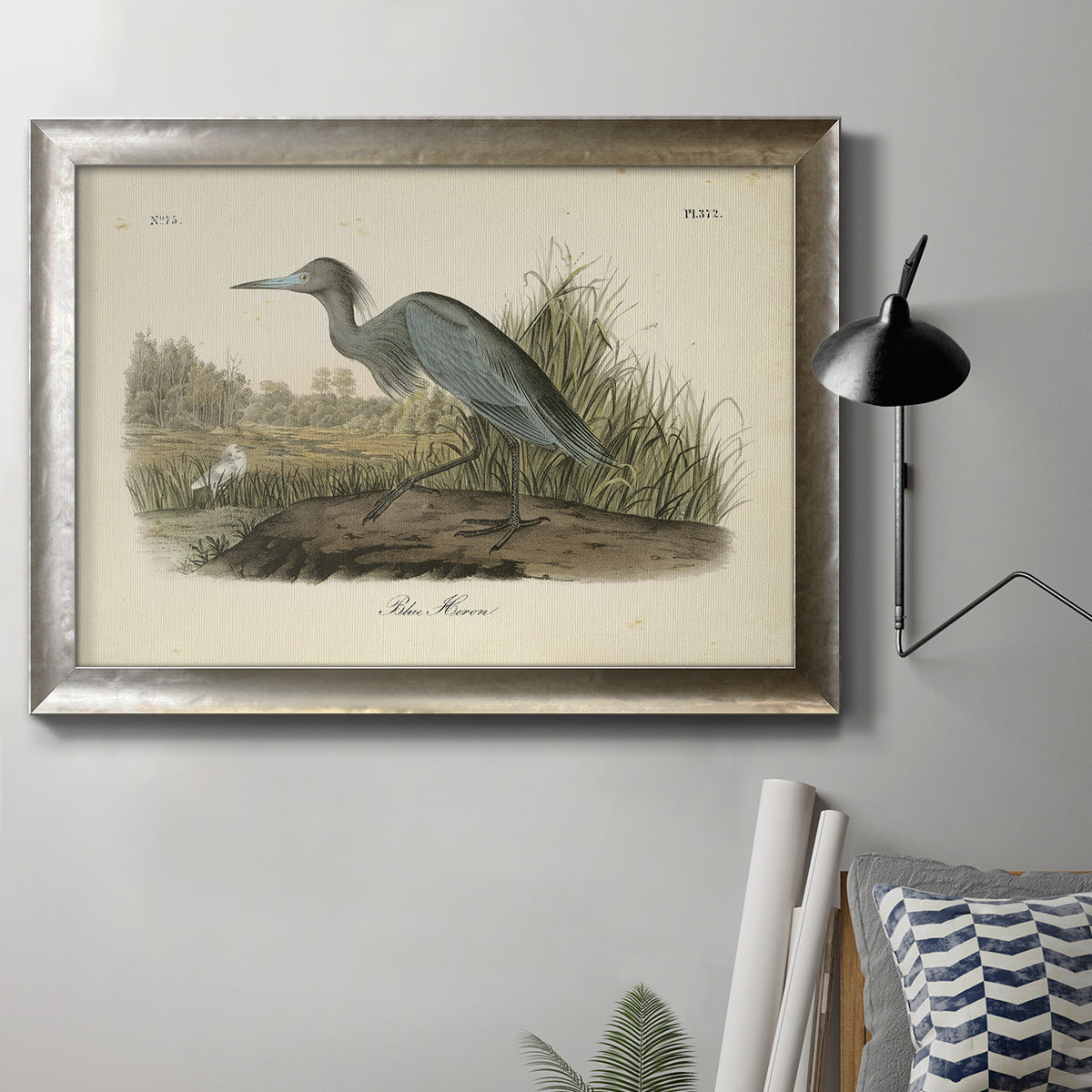 Antique blue heron bird illustration by John James Audubon in an ornate mottled silver frame displayed in a neutral interior setting.