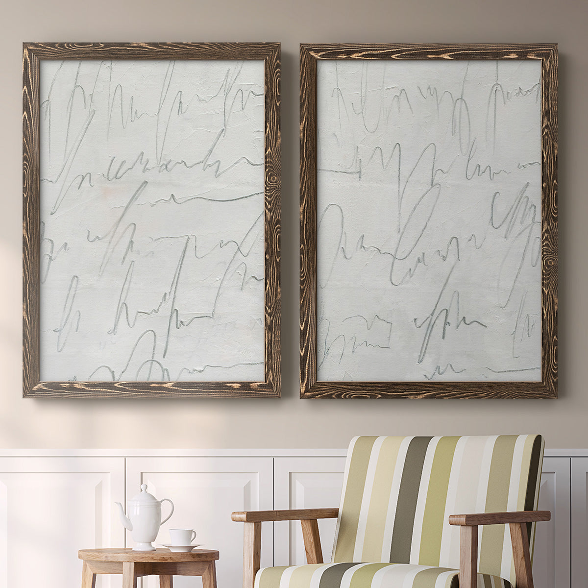 Set of two walnut barnwood framed canvas prints depicting two minimalist script abstracts featuring faint looping handwriting across pale gray grounds above a sideboard in a cozy sitting room.