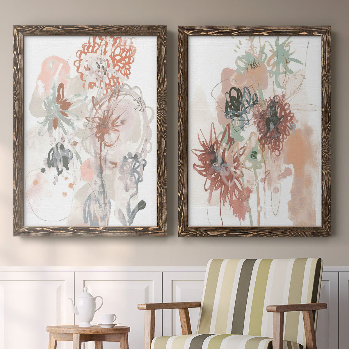 Set of two walnut barnwood framed canvas prints depicting two abstract watercolor botanicals featuring loose blush gray and coral floral gestures above a sideboard in a cozy sitting room.