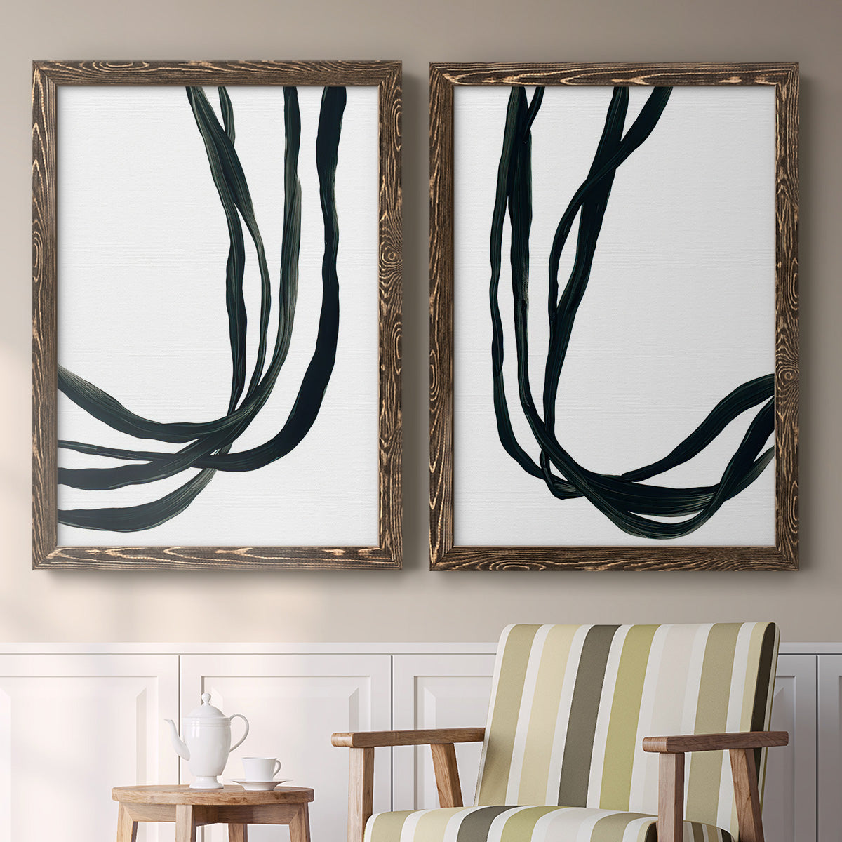Set of two walnut barnwood framed canvas prints depicting two minimalist gestural line abstracts featuring flowing black ribbon-like lines above a sideboard in a cozy sitting room.