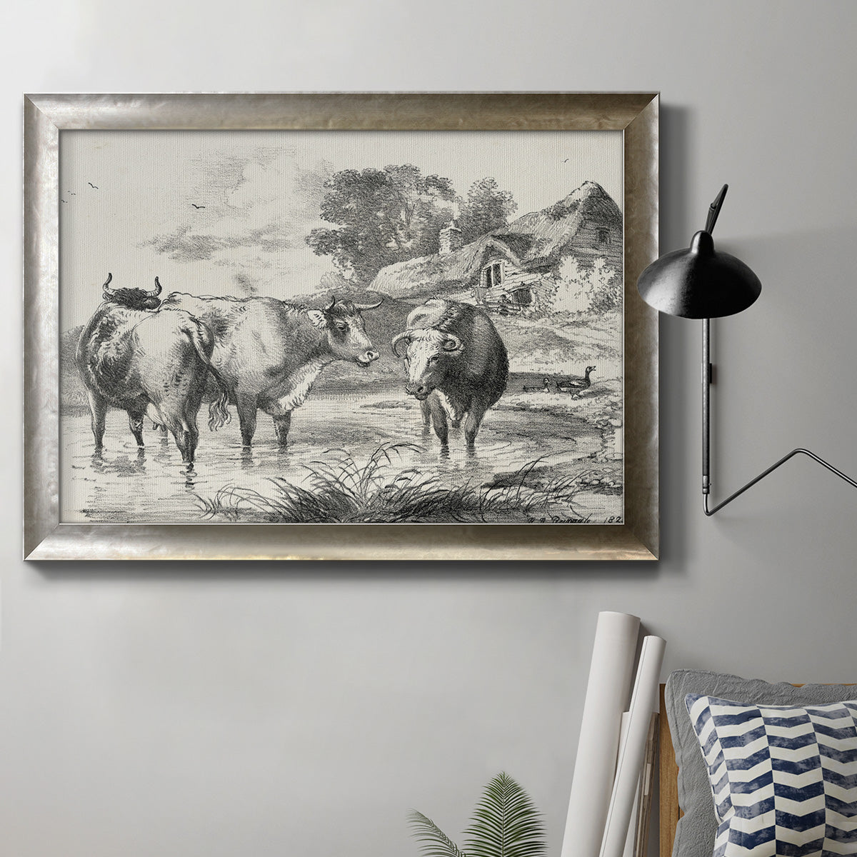 Classical rural landscape artwork by Nicolas Berchem in an ornate mottled silver frame displayed in a neutral interior setting.