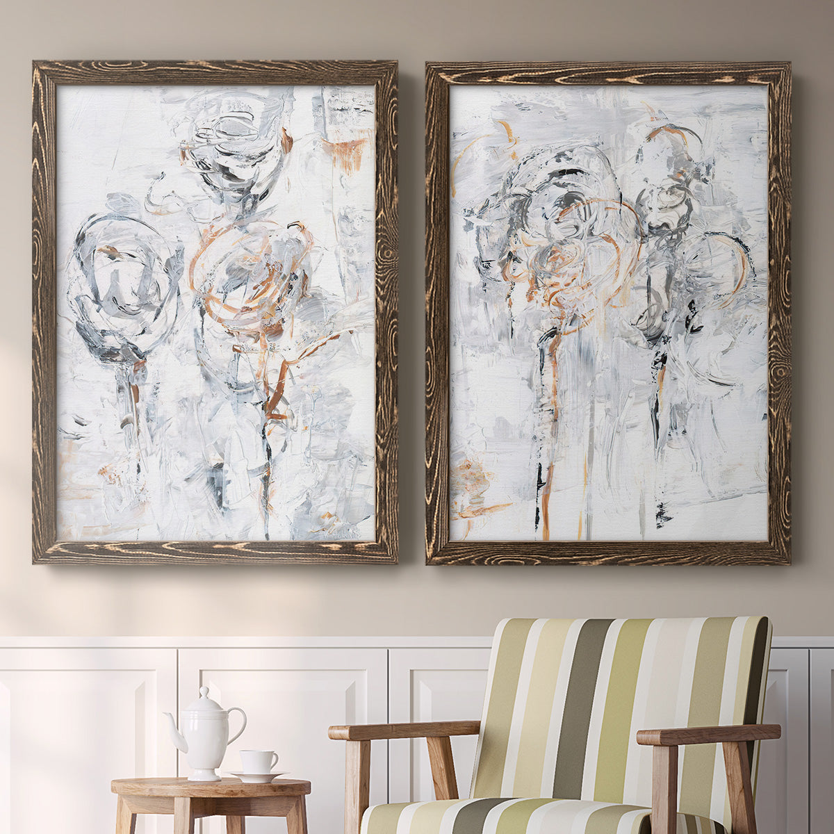 Set of two walnut barnwood framed canvas prints depicting two expressive floral abstracts featuring loosely suggested flowers and stems in pale gray and peach above a sideboard in a cozy sitting room.