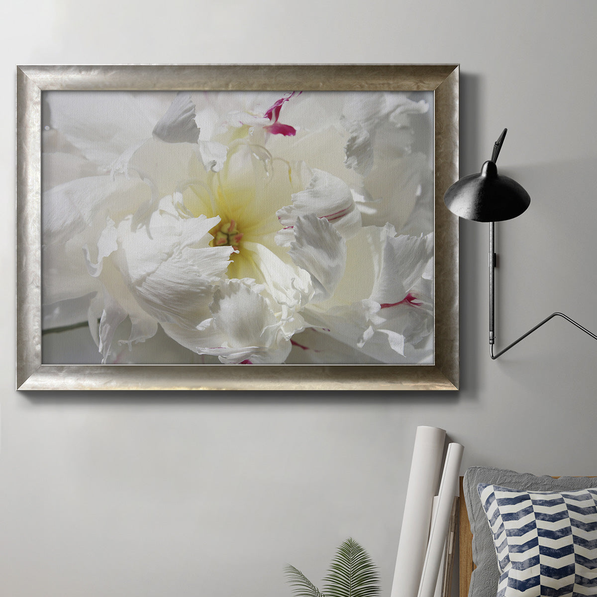 Close up view of peony petals in an ornate mottled silver frame displayed in a neutral interior setting.