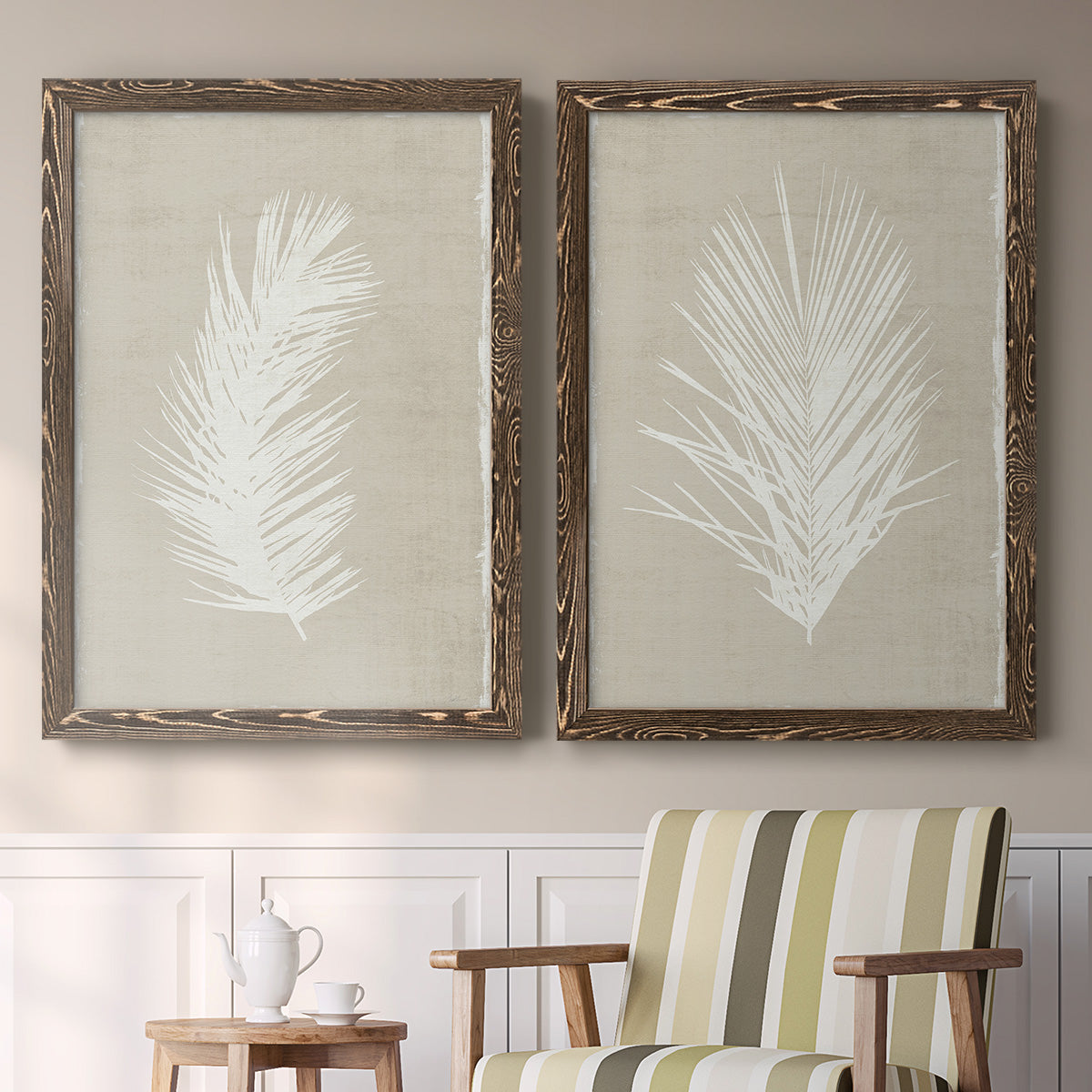 Set of two walnut barnwood framed canvas prints depicting two minimalist tropical botanical prints featuring white palm frond silhouettes above a sideboard in a cozy sitting room.