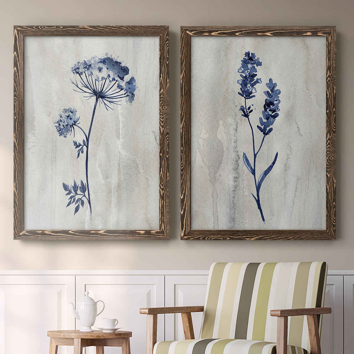 Set of two walnut barnwood framed canvas prints depicting two rustic monochrome botanical paintings featuring blue wildflower stems on weathered neutral paper above a sideboard in a cozy sitting room.